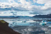 a glacier with clouds reflecting