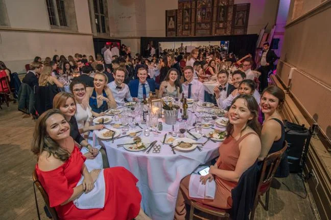 Students at the Winter Ball sitting at a round formal table with food and drink.