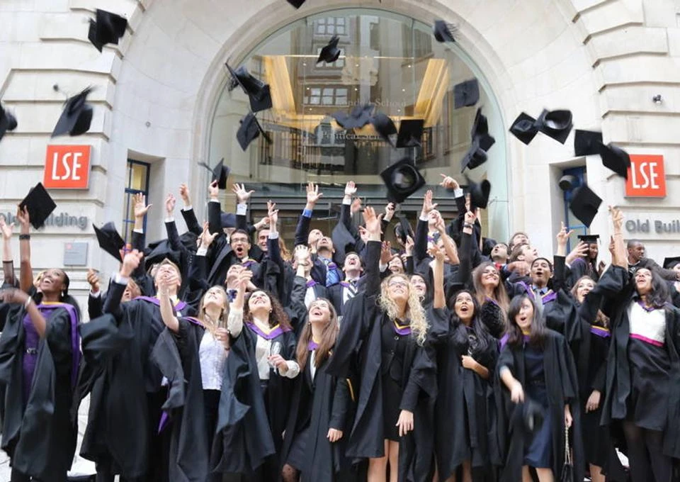 LSE graduates throwing their caps outside the Old Building at graduation