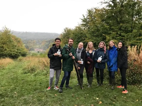 A group of students and staff posing with Juniper Hall in the background.
