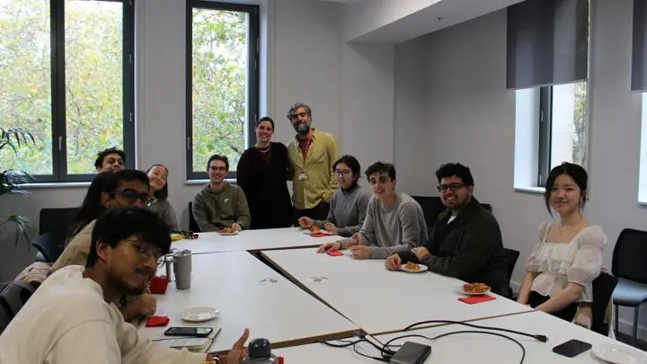 Students sitting round a table with pizza.