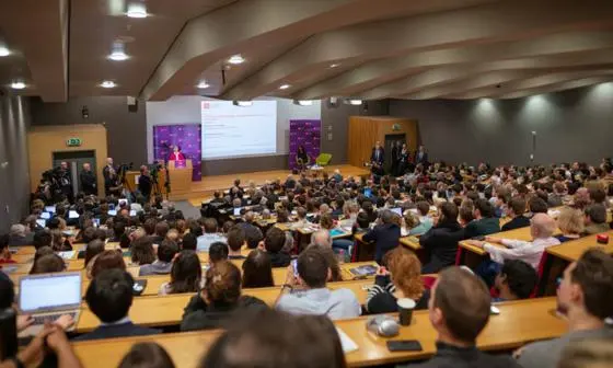 a photo of a lecture hall filled with students, from the back of the room