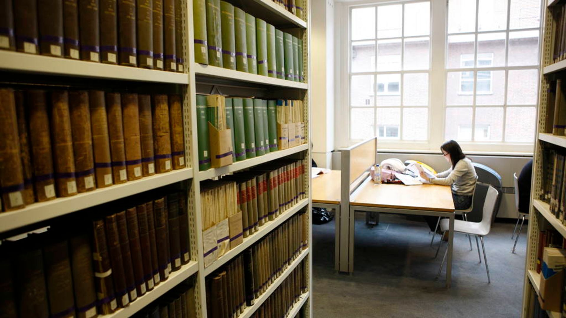 Book stacks and someone sat at a desk.