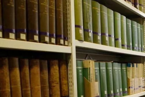 Book stacks and someone sat at a desk.
