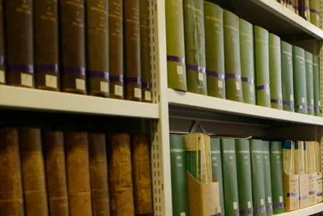 Book stacks and someone sat at a desk.