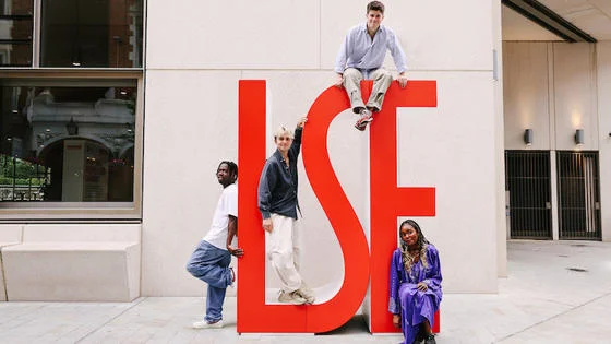 students standing against LSE logo