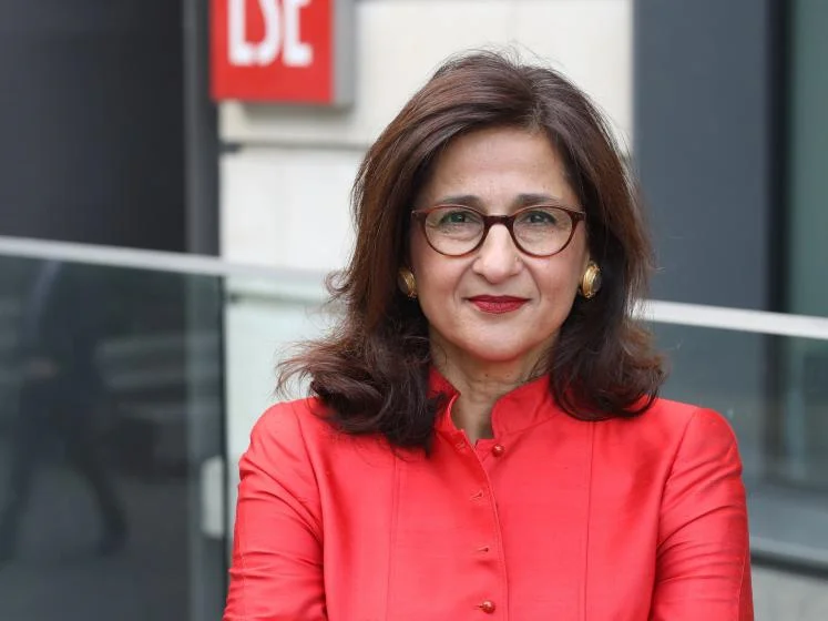 Former LSE President Minouche Shafik stands in a pink jacket front of an LSE building
