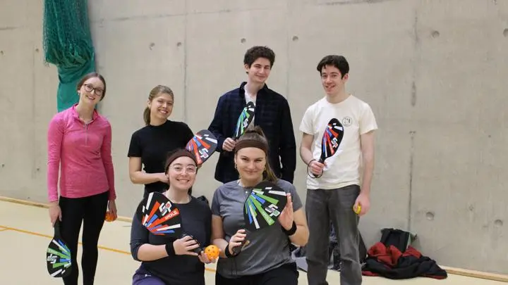 Students wearing activewear and holding paddles.