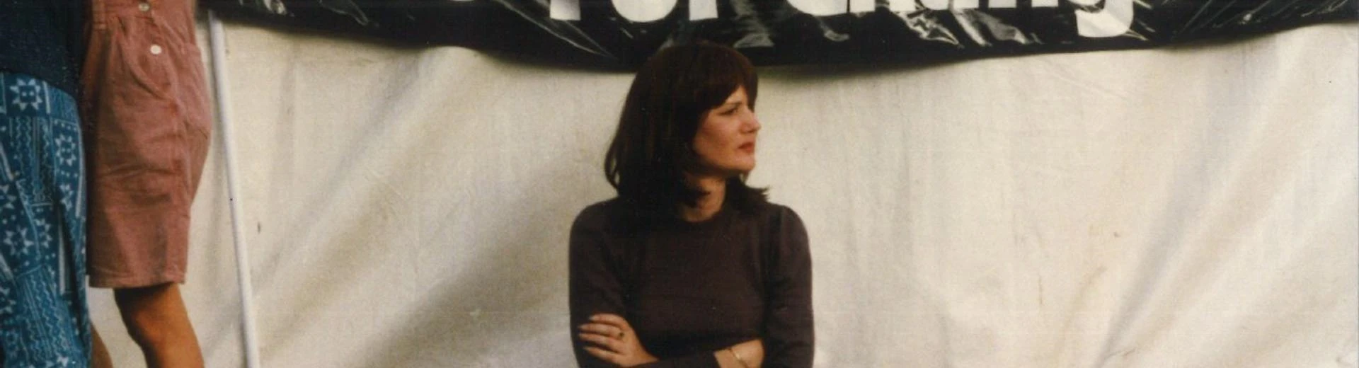A person sat up against a tent with a sign behind them.