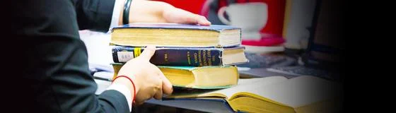Student lifting pile of books from desk