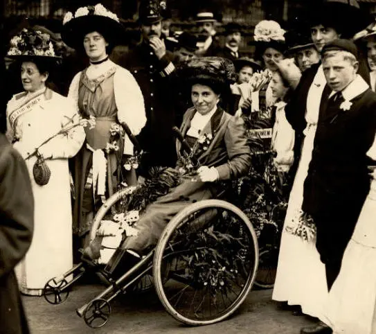 Rosa May Billinghurst sitting in her tricycle surrounded by people
