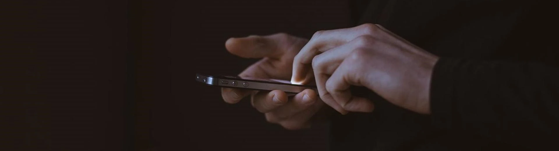 hands typing on a smartphone in the dark