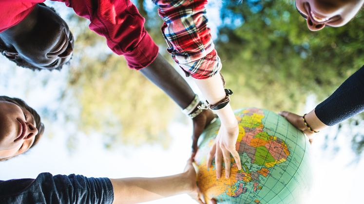 Diverse students holding up a globe - iStock