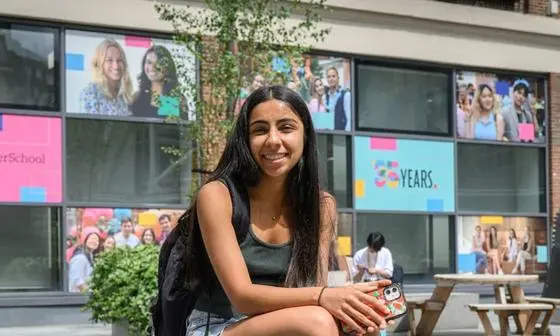 A student sat outside LSE Library and smiling.
