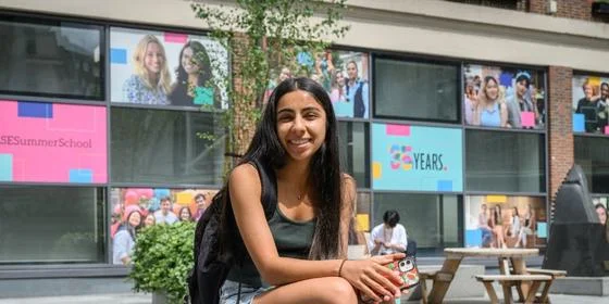 A student sat outside LSE Library and smiling.