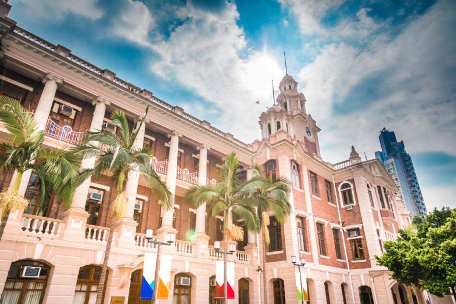 The University of Hong Kong main building with palm trees in sunlight