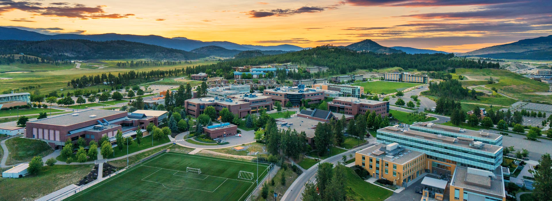 UBC campus grounds including sports pitches and views to the surrounding mountains at sunrise