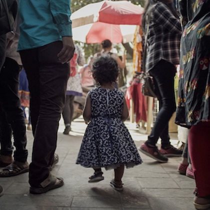 the back of a toddler walking through a busy street