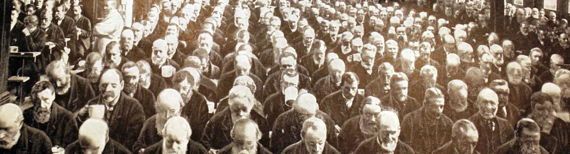Workhouse dinner with lots of men lined up eating.