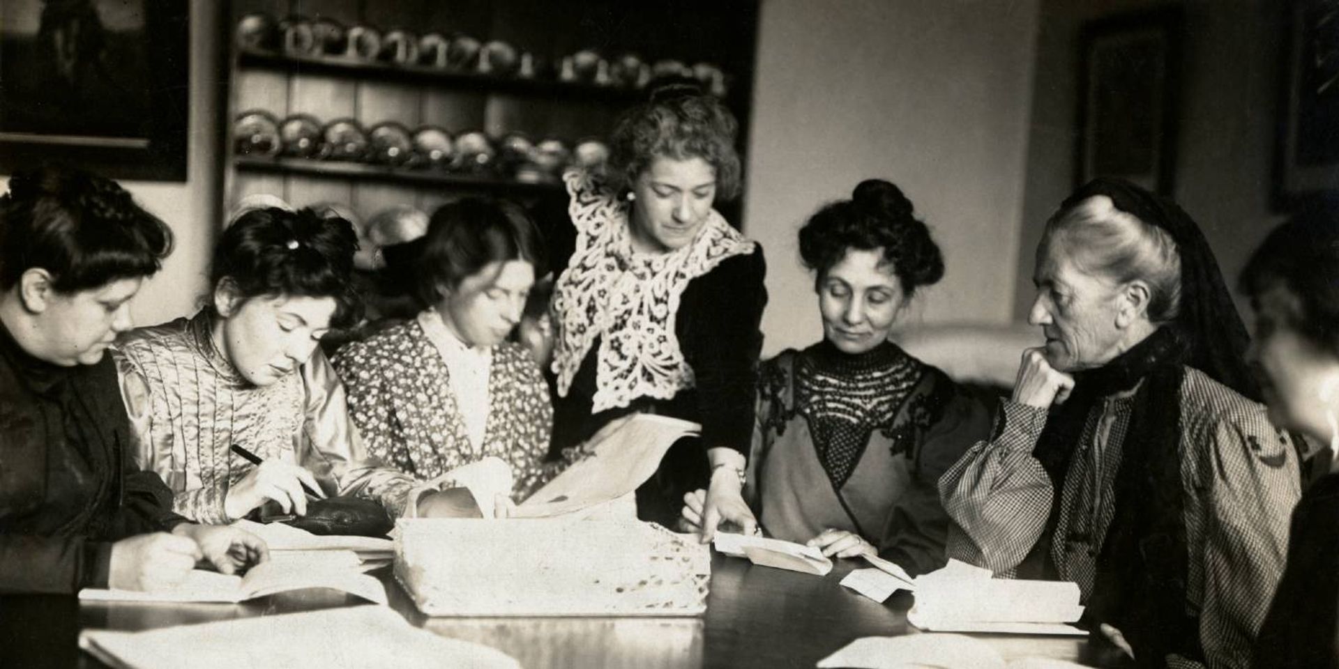 WSPU leaders sitting around a table looking at papers together and writing.