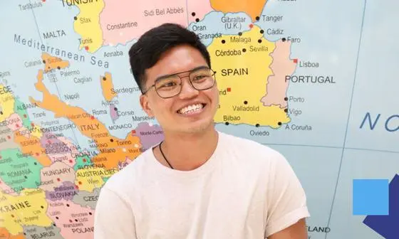 An LSE student standing beside a world map