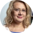 Headshot of Iryna small smile wearing glasses and with shoulder length blond hair.
