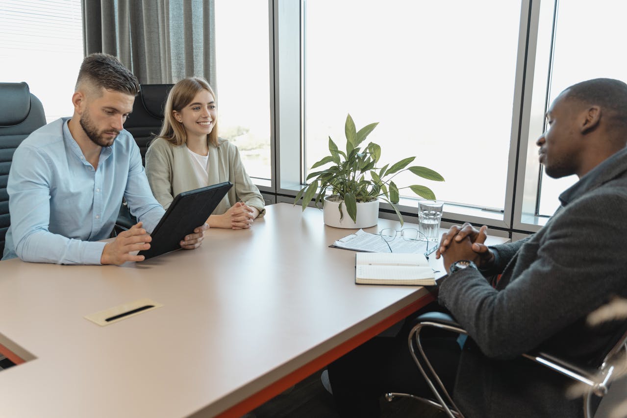 Business meeting with three people reviewing a tablet
