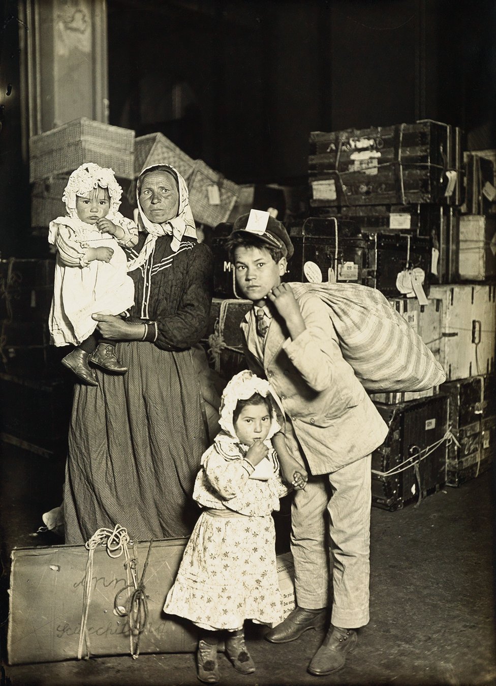 Italian family (mother and children) in the baggage room, Ellis Island, 1905
