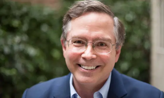 Headshot of a man in front of a wall with ivy