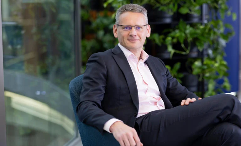 John Mark Pettigrew sits in a chair looking confidently out to the viewer