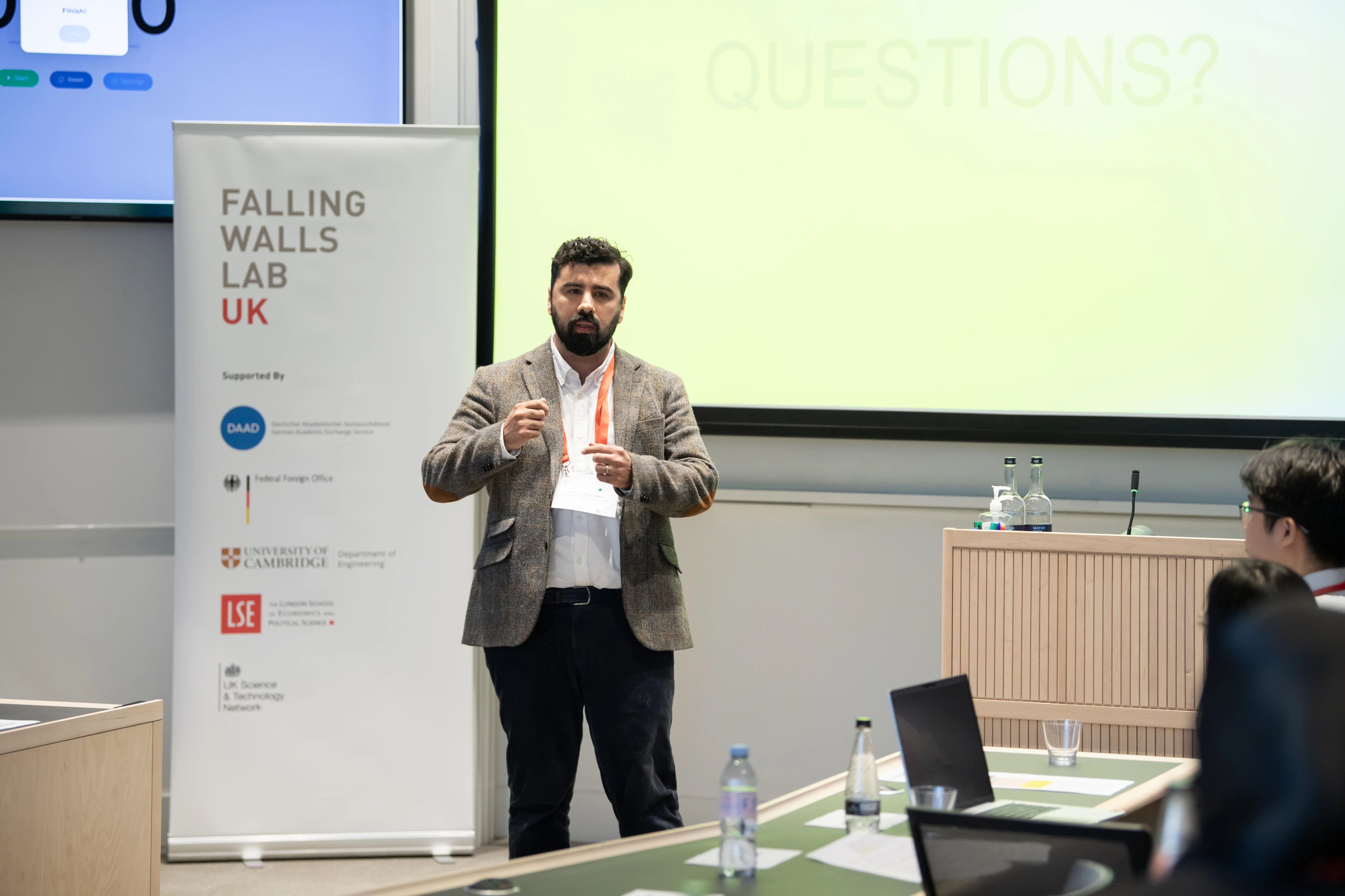 LSE PhD student, Juan Pablo Calderon Meza, in front of a screen presenting at the Falling Walls lab.