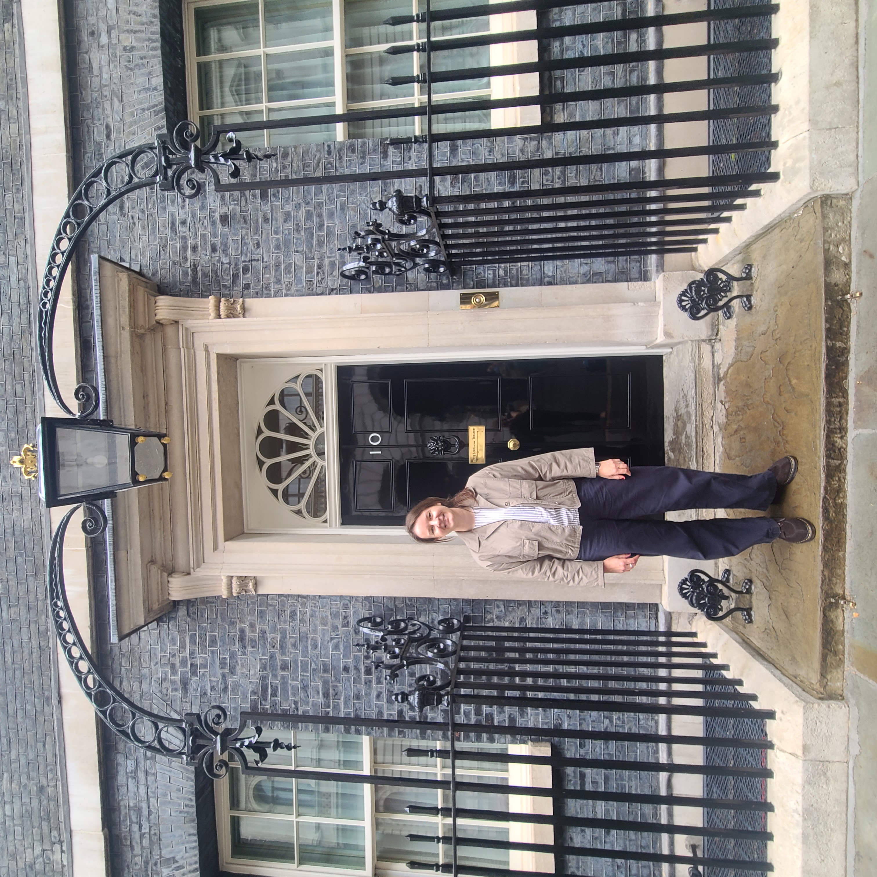 a researcher stands on the steps of number 10 downing street
