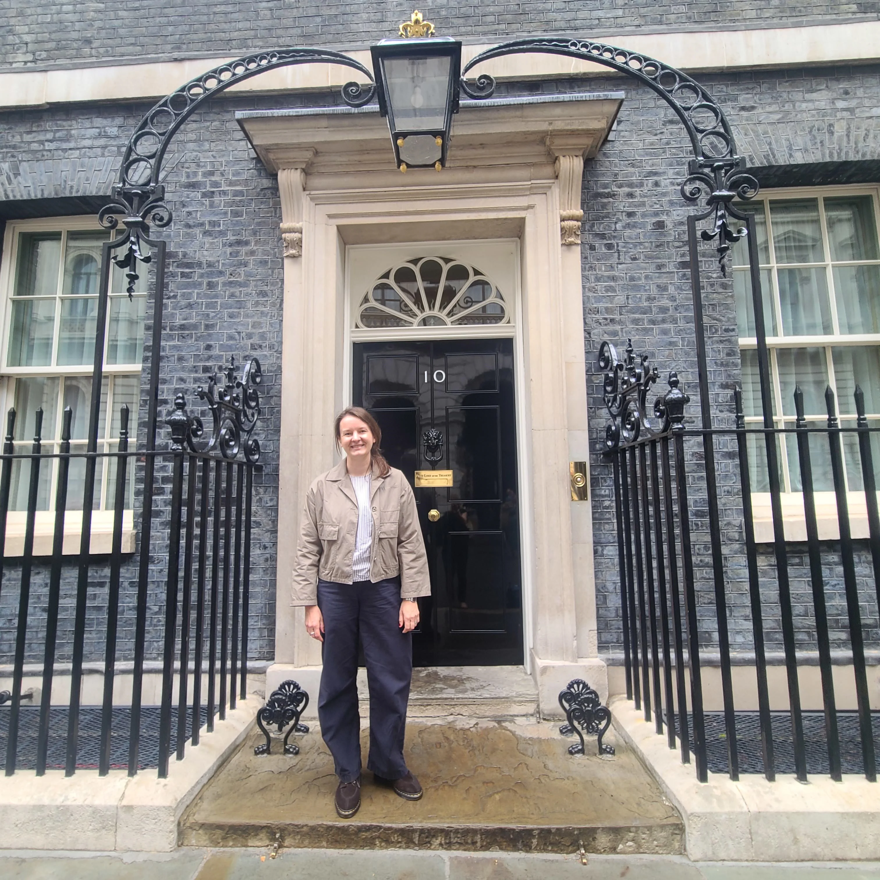 a researcher stands on the steps of number 10 downing street