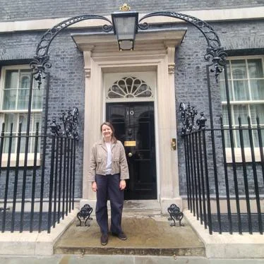 a researcher stands on the steps of number 10 downing street