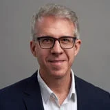 headshot of a man with glasses smiling at the camera