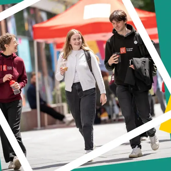 Three students smiling and walking on campus