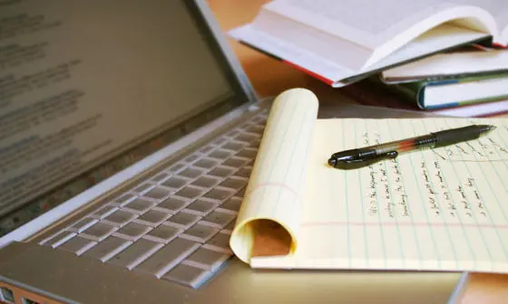 Photo of a laptop computer with handwritten notes beside it