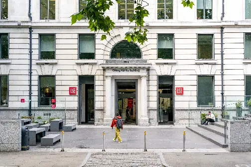 Student walking in front of LSE building wearing backpack