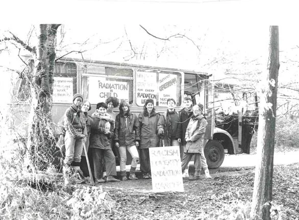 A group of people with placards stood in front of a bus.