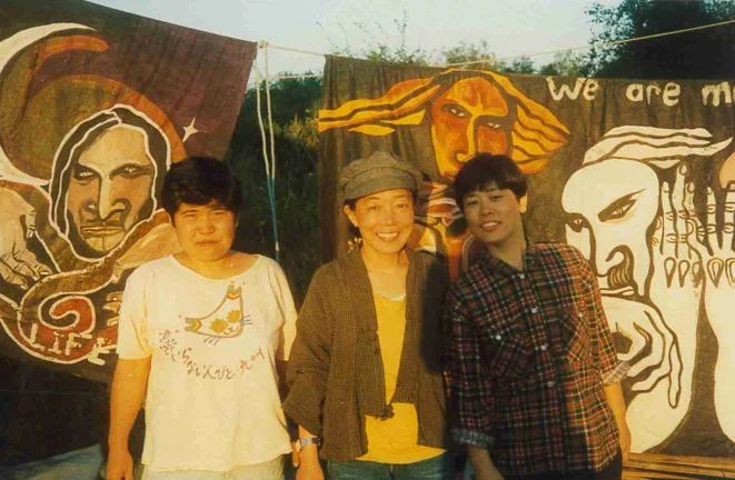 Three people stood together in front of banners.