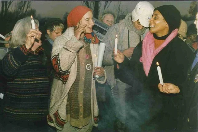 A group fo omen holding candles and smiling at each other.