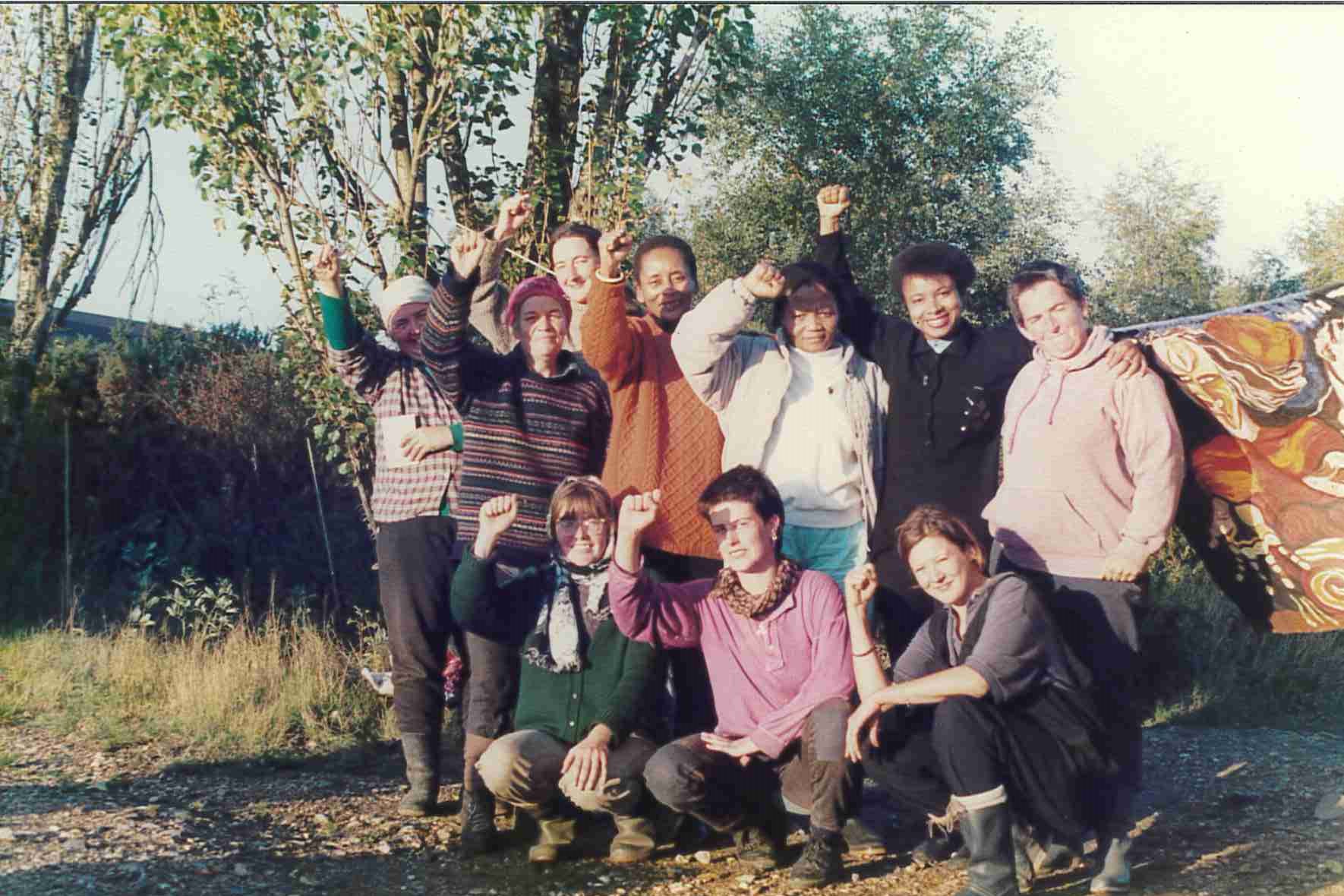 A group of people gathered outside for a group photo. Most have clenched fists in the air. 