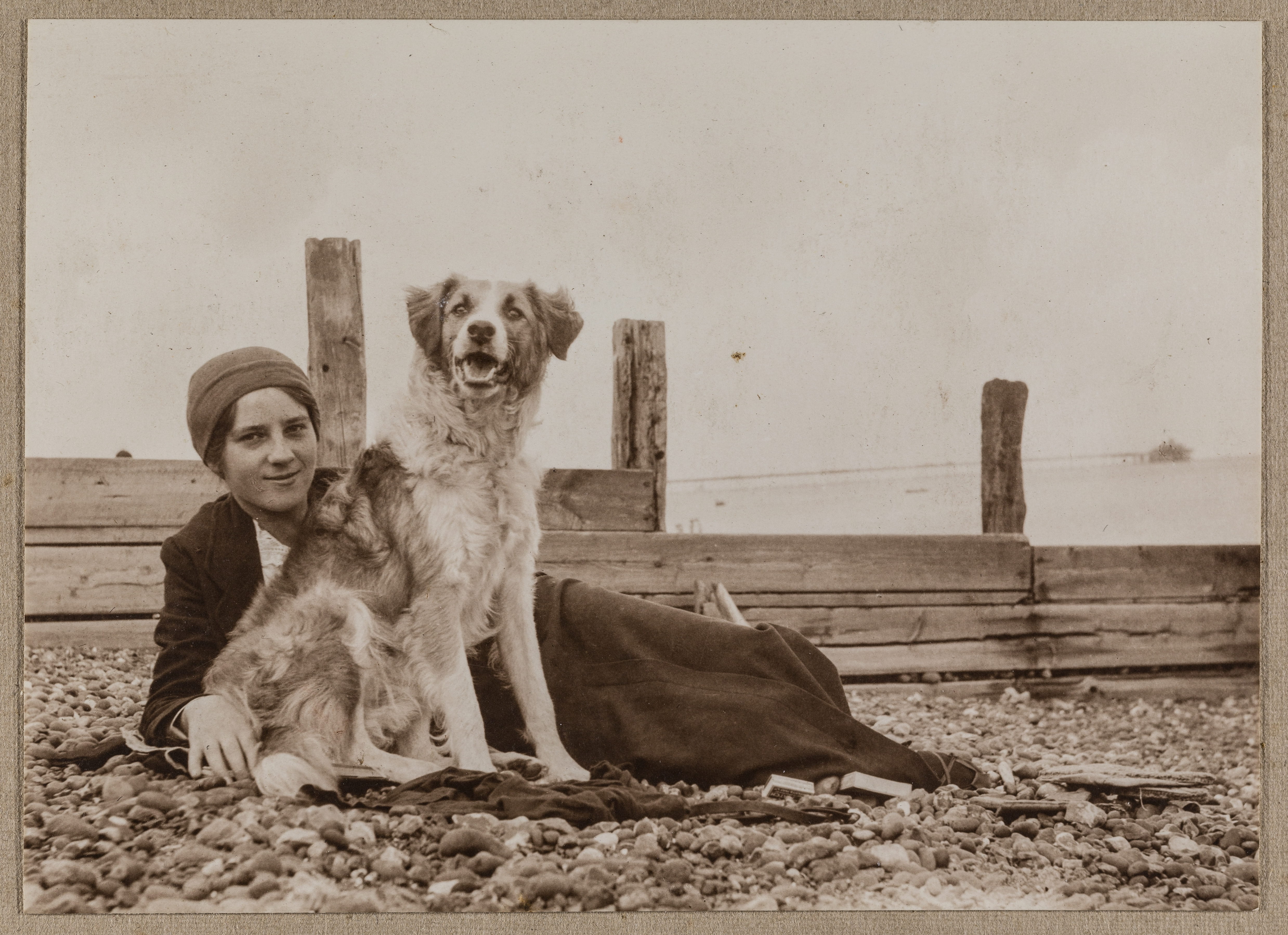 Elsie Duval laying on a beach with a dog