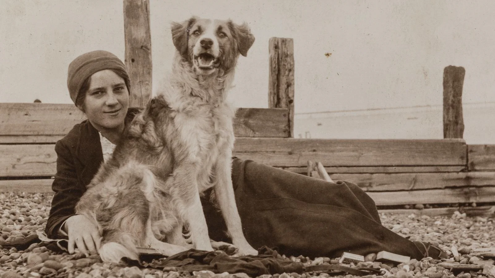 Elsie Duval laying on a beach with a dog