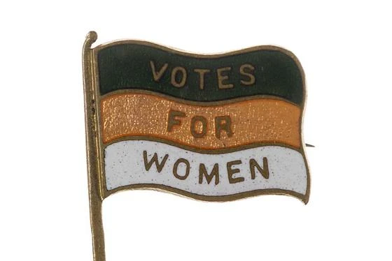 A green, gold and white Women's Freedom League badge with Votes For Women written on it.