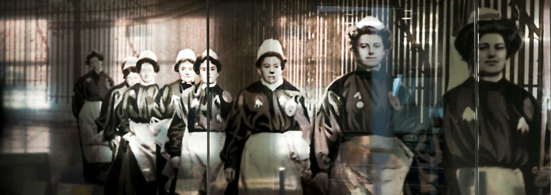 A glass panel with a feature photo of suffragettes marching