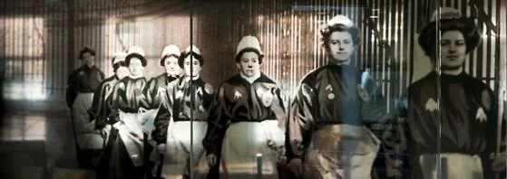 A glass panel with a feature photo of suffragettes marching