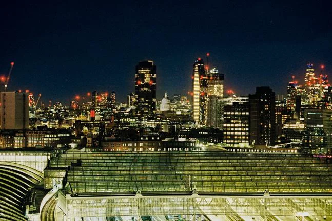nighttime photo of train station and london skyline