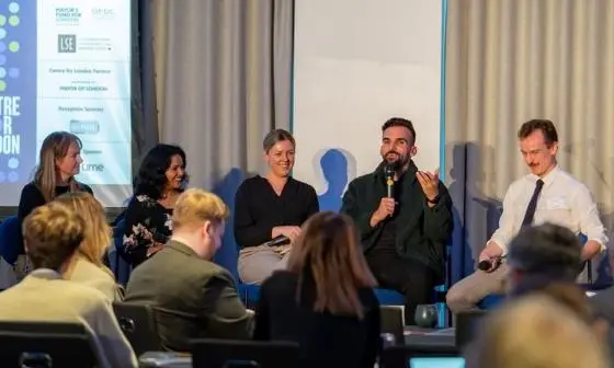 Five people sit at a panel with an audience.