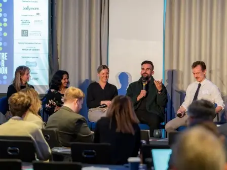 Five people sit at a panel with an audience.